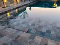 Escalones de piscina con diversos tipos de gresite para piscinas, creando un mosaico de tonos grises, azules y marrones.