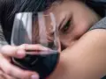 Smutna kobieta z kieliszkiem wina, jakby słuchała piosenki o alkoholu.