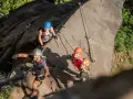 Uśmiechnięci ludzie na via ferracie w Czechach, pokonujący skalną ścianę.