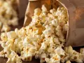 Popcorn rieselt aus einer Papiertüte. Ein perfekter, leichter Snack für zwischendurch.