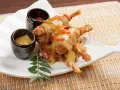Ancas de rana crujientes con salsa dorada y gominolas rojas, acompañadas de dos salsas. Una deliciosa receta francesa.