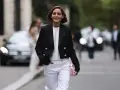 Mujer sonriente con chaqueta negra y pantalones blancos, lista para una comida familiar de invierno.