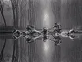 Rzeźby w stawie, koń i ludzie, odbijają się w wodzie. Styl Michael Kenna.