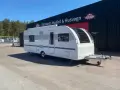 En vit Adria Alpina 613 UT husvagn står parkerad framför en byggnad med texten "Vincents Husbil & Husvagn".