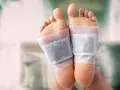 Close-up of feet with detox patches applied to the soles, demonstrating how to do a foot detox at home.