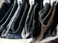 Stosy jeansów na wieszakach. Dowiedz się, co zrobić, żeby jeansy nie farbowały i zachowały swój kolor.