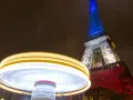 Manège lumineux tournant devant la Tour Eiffel illuminée en bleu, blanc et rouge. Une scène de Paris nocturne, parmi les plus belles photos de nuit.