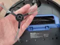 Eine Hand hält eine Seitenbürste eines Saugroboters. So funktioniert ein Saugroboter: Die Bürsten fegen Schmutz zur Hauptbürste.