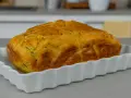 Sformato di zucchine dorato e fragrante, appena sfornato, servito in una pirofila bianca.