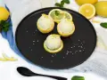 Erfrischendes zitroneneis in zitrone, garniert mit Minze und bunten Streuseln auf schwarzer Platte.
