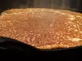 En gyllene, nygräddad pannkaka steker i en gjutjärnspanna. Perfekt för en glutenfri frukost eller fika.