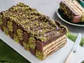 Torta fredda con strati di biscotti, crema e cioccolato, decorata con granella di pistacchio. Un tripudio di dolci al pistacchio.