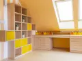 Luminosa mansarda con pareti arancioni e mobili in legno chiaro. Le idee colori pareti mansarda sono valorizzate da cubi contenitori gialli e un'ampia scrivania.