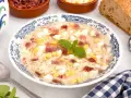 Sopa de picadillo andaluza en un plato azul y blanco con trocitos de huevo duro, jamón y fideos finos.
