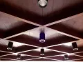 Drewniane, kratownicowe **stare kasetony na suficie** z wbudowanymi reflektorami tworzą geometryczny wzór.