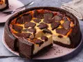 Ein saftiger russischer Zupfkuchen mit dunklem Schokoladenboden und cremiger Füllung, belegt mit zupfartigen Schokoladenstückchen.