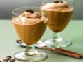 Due bicchieri di spumone al caffè, guarniti con chicchi di caffè, su un tavolo verde.