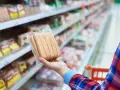 Ręka trzyma paczkę parówek w supermarkecie. Zastanawiasz się, ile kalorii ma parówka?