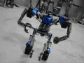 Metalowy robot z niebieskimi akcentami, wyglądający jakby właśnie opuścił fabrykę robotów w Mosznej.