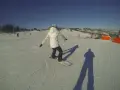 Osoba na snowboardzie na stoku narciarskim, ucząca się w szkole narciarskiej Budzyńskich. Słoneczny dzień, czyste niebo.