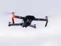 A drone hovers in the sky, its red lights blinking. Planning a trip? Be aware of Bahamas drone laws before you fly.