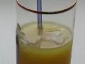 Orzeźwiający gin z sokiem pomarańczowym, z kostkami lodu i niebieską słomką.
