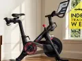 A Peloton bike, perfect for indoor cycling vs spinning, sits in a bright room. A yellow graphic promotes "Indoor Training Week.