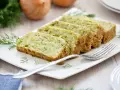 Fette di flan di zucchine su un piatto bianco, guarnite con aneto. Una forchetta argentata è appoggiata sul piatto.