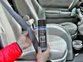 Ręce trzymają pas bezpieczeństwa i puszkę z napisem "Silikonspray". Dowiedz się, jak usunąć silikon z materiału w samochodzie.