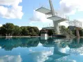 Sprungturm im Schwimmbad Pankow spiegelt sich im klaren Wasser. Ein sonniger Tag lädt zum Sprung ein.