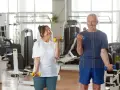 Uśmiechnięta para seniorów ćwiczy z hantlami na siłowni.
