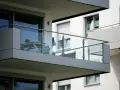 Nowoczesna loggia z przeszkloną balustradą, na której stoi stolik z kwiatami i krzesło.