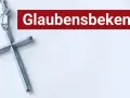 Ein silbernes Kreuz liegt neben dem Schriftzug "Glaubensbekenntnis".