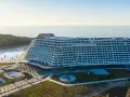 Nowoczesny, falisty pobierowo nowy hotel z basenami i widokiem na morze, otoczony lasem.