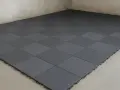 Dalles modulaires grises posées sur un sol de garage. L'épaisseur de la dalle béton garage est ici optimisée par ce revêtement pratique.