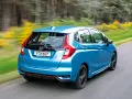 Blauer Honda Jazz Hybrid fährt auf einer Landstraße. Trotz der schönen Fahrt gibt es Berichte über Honda Jazz Hybrid Probleme.