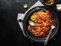 Un piatto di spaghetti alla carrettiera fumanti, conditi con un ricco sugo di pomodoro e basilico fresco, su sfondo scuro.