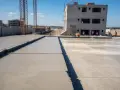 Plac budowy z wylewanym betonem na fundamenty. Widać budynek w stanie surowym, dźwigi i pracowników. Jaki beton na fundament b20 czy b25?