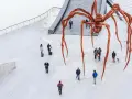 Une immense araignée de bronze, œuvre de Louise Bourgeois, domine une place où quelques passants curieux l'observent.