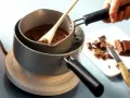 Delikatne topienie czekolady w kąpieli wodnej, by uzyskać idealną konsystencję. Drewniana łyżka miesza płynną masę.