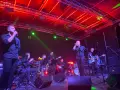 Zespół gra warszawskie piosenki podwórkowe na scenie oświetlonej czerwonymi i zielonymi światłami.