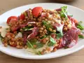 Insalata di lenticchie con pomodorini, scaglie di parmigiano e prosciutto crudo, un piatto fresco e gustoso.