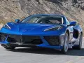 Błękitny Chevrolet Corvette Stingray pędzi po pustynnej drodze.