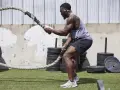 Mężczyzna w sportowym stroju ćwiczy z grubą liną, wykonując ruchy, które przypominają pracę z epoki wikingów.