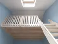 Jasna, drewniana antresola z balustradą i schodami, podświetlona przez okno dachowe.