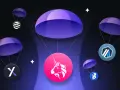 Co to jest airdrop kryptowaluty? Ilustracja pokazuje kilka tokenów kryptowalutowych spadających na spadochronach, symbolizując darmowe rozdawanie cyfrowych aktywów.