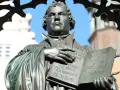 Martin Luther hält eine Bibel. Er erinnert uns daran, wer am Reformationstag frei hat.
