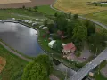 Jonsboda camping vid en kanal med husbilar, båtar och röda stugor. En bro leder över vattnet.