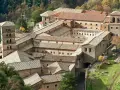 Aerial view of a sprawling monastery complex near Rome, with terracotta roofs and a tall bell tower.