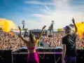 DJ-ka i DJ na scenie, płomienie buchają, tłum szaleje na festiwalu muzyki elektronicznej.